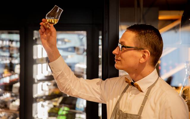 Barkeeper hält ein Glas Whisky nach oben