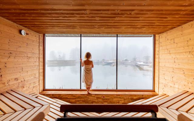 Frau am Panoramafenster der Sauna im Pfalzblick Wald Spa Resort