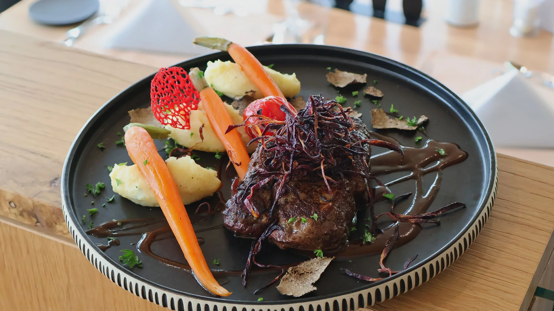 Ihr Hotel im Dahner Felsenland: Pfalzblick Wald Spa Resort Gebratenes Fleisch mit Karotten, Kartoffelpüree und dunkler Sauce auf einem schwarzen Teller