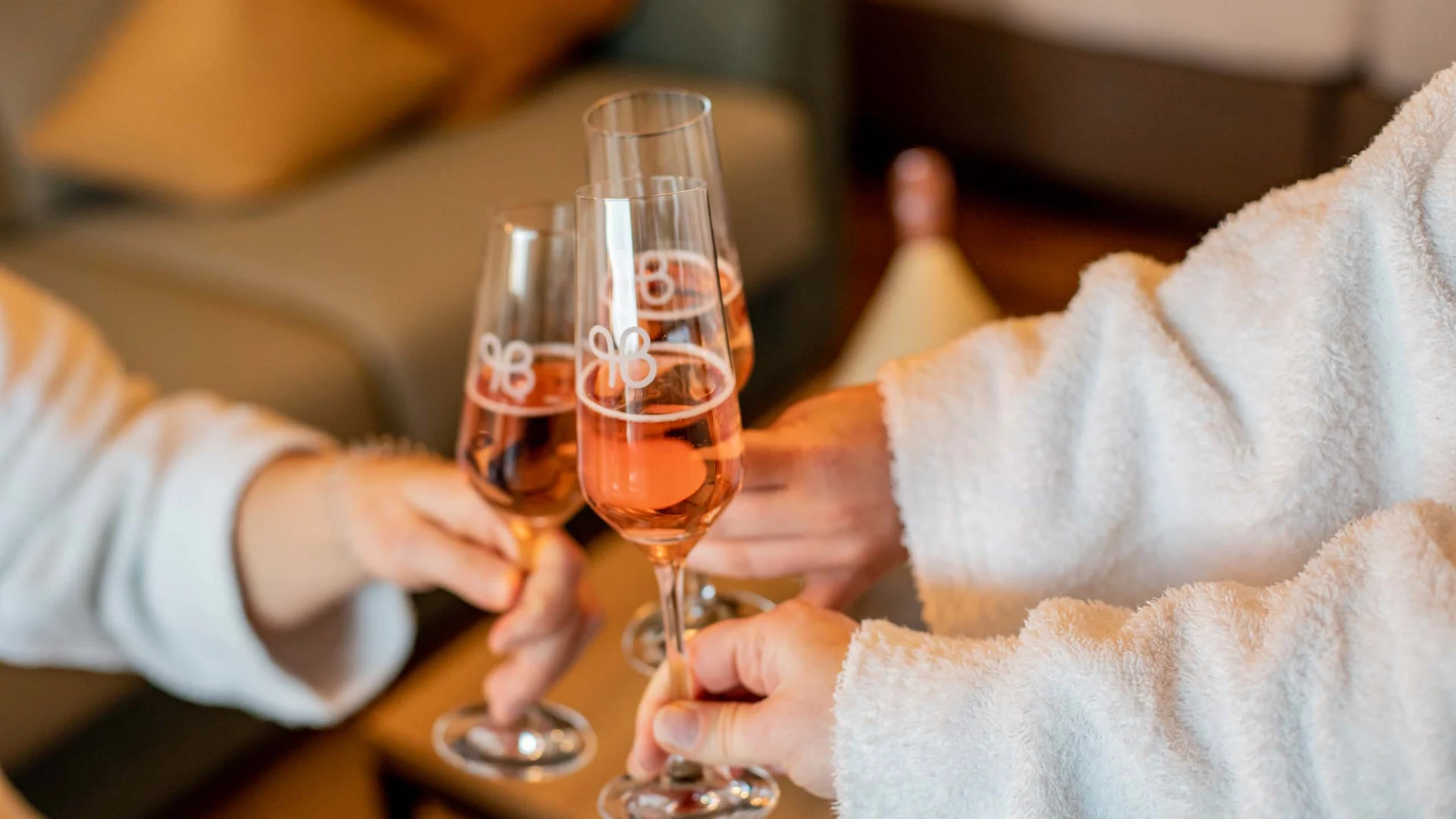 Ihr Hotel im Dahner Felsenland: Pfalzblick Wald Spa Resort Drei Personen stoßen mit Sektgläsern in Bademänteln an