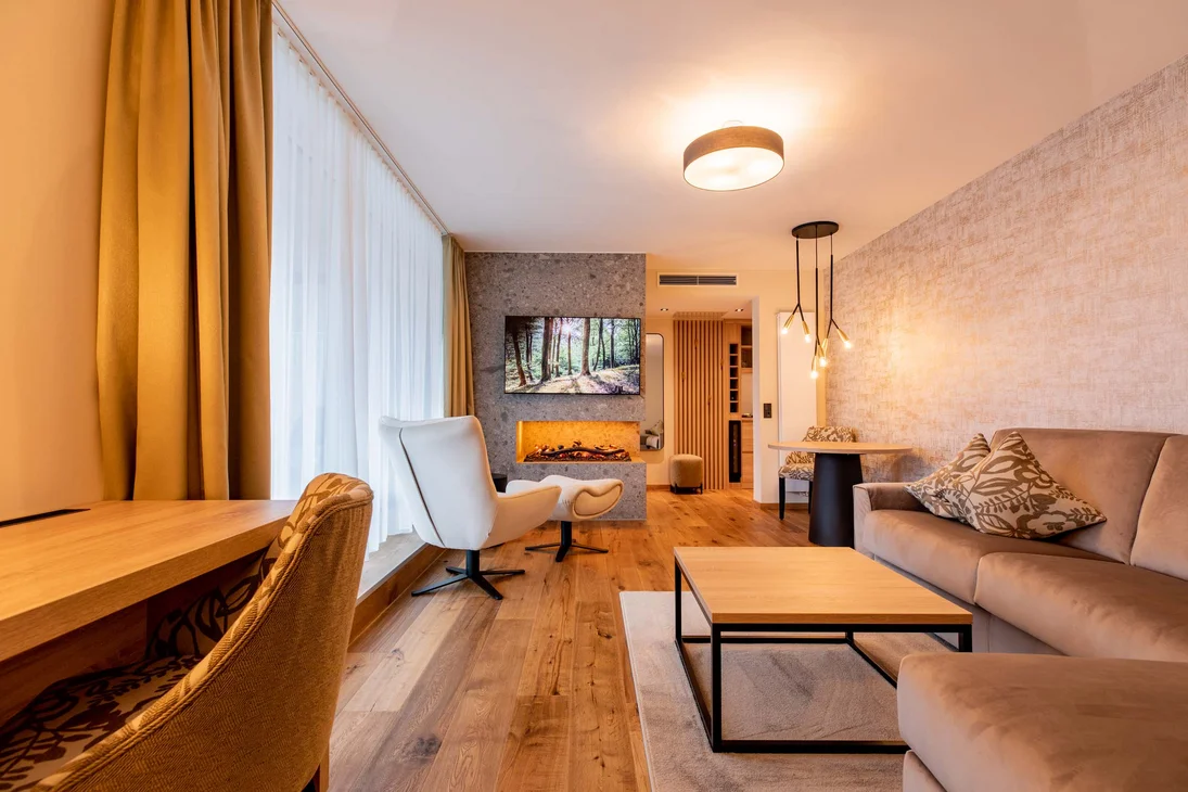 Ihr Hotel im Dahner Felsenland: Pfalzblick Wald Spa Resort Wohnzimmer mit Kamin, Fernseher, Sesseln und Sofa in warmem Design