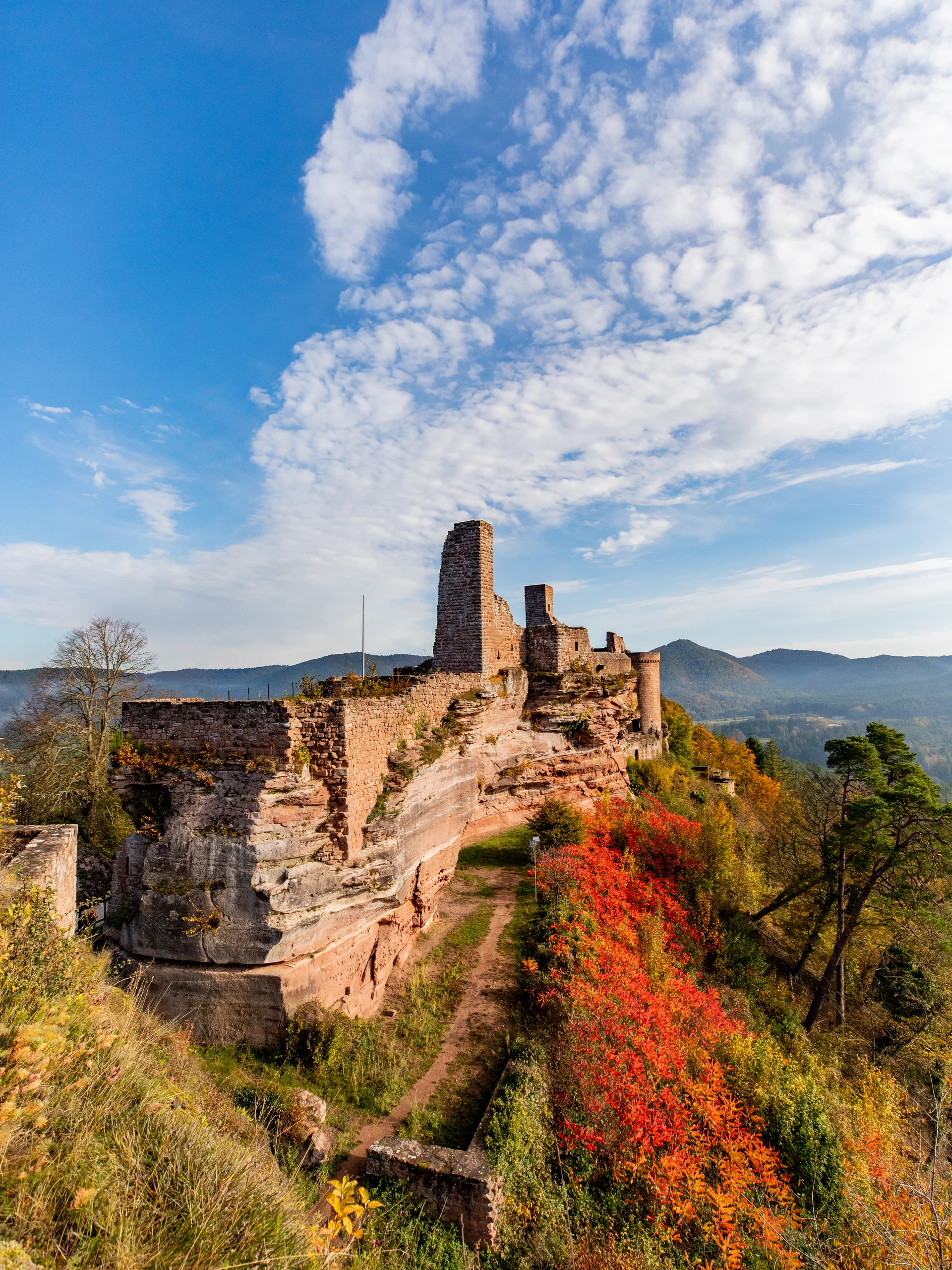 Ihr Hotel im Dahner Felsenland: Pfalzblick Wald Spa Resort Ruine einer Burg auf einem Hügel mit Herbstlaub und blauem Himmel