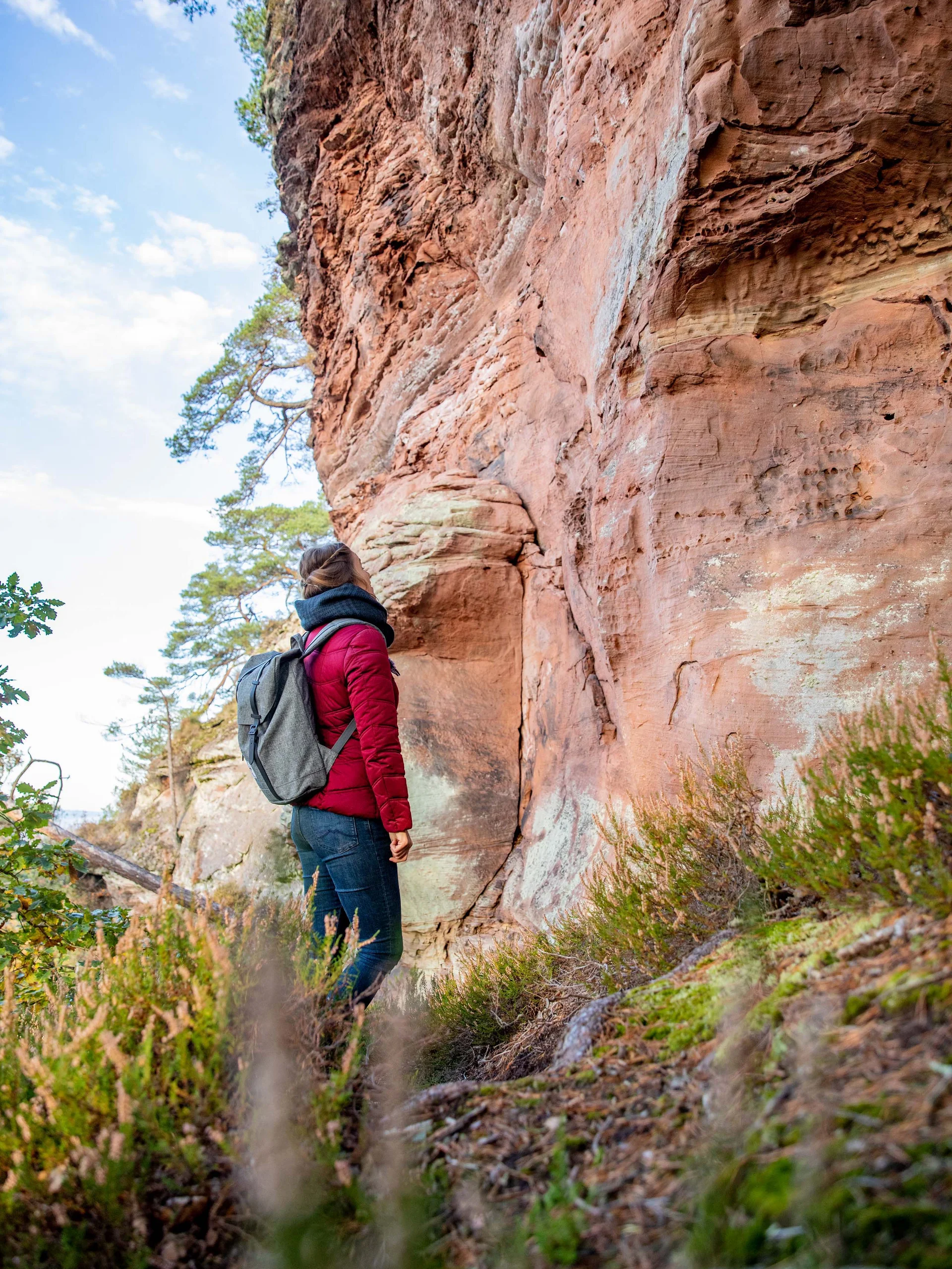 Pfalzblick: your nature hotel in Rhineland-Palatinate Woman in red jacket standing by red rock formations in forest