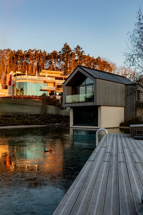 Ihr Hotel im Dahner Felsenland: Pfalzblick Wald Spa Resort Moderner Bungalow am Ufer eines Sees bei Sonnenuntergang