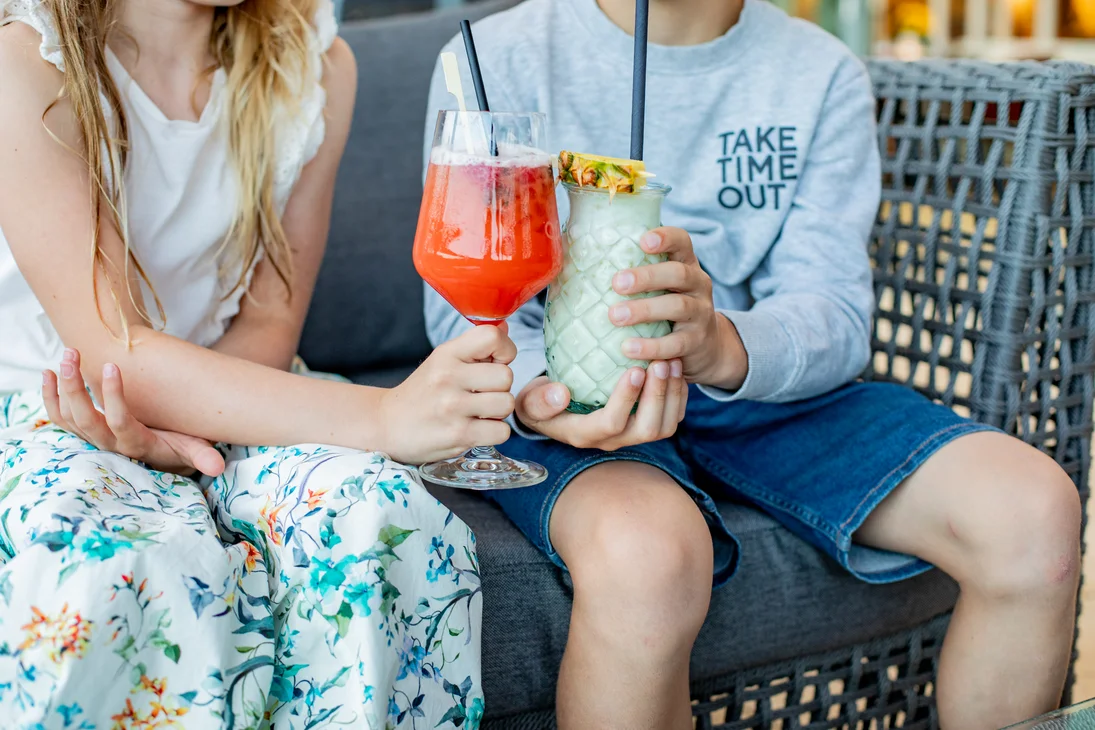 Ihr Hotel im Dahner Felsenland: Pfalzblick Wald Spa Resort Zwei Kinder halten bunte Getränke in Gläsern und sitzen zusammen