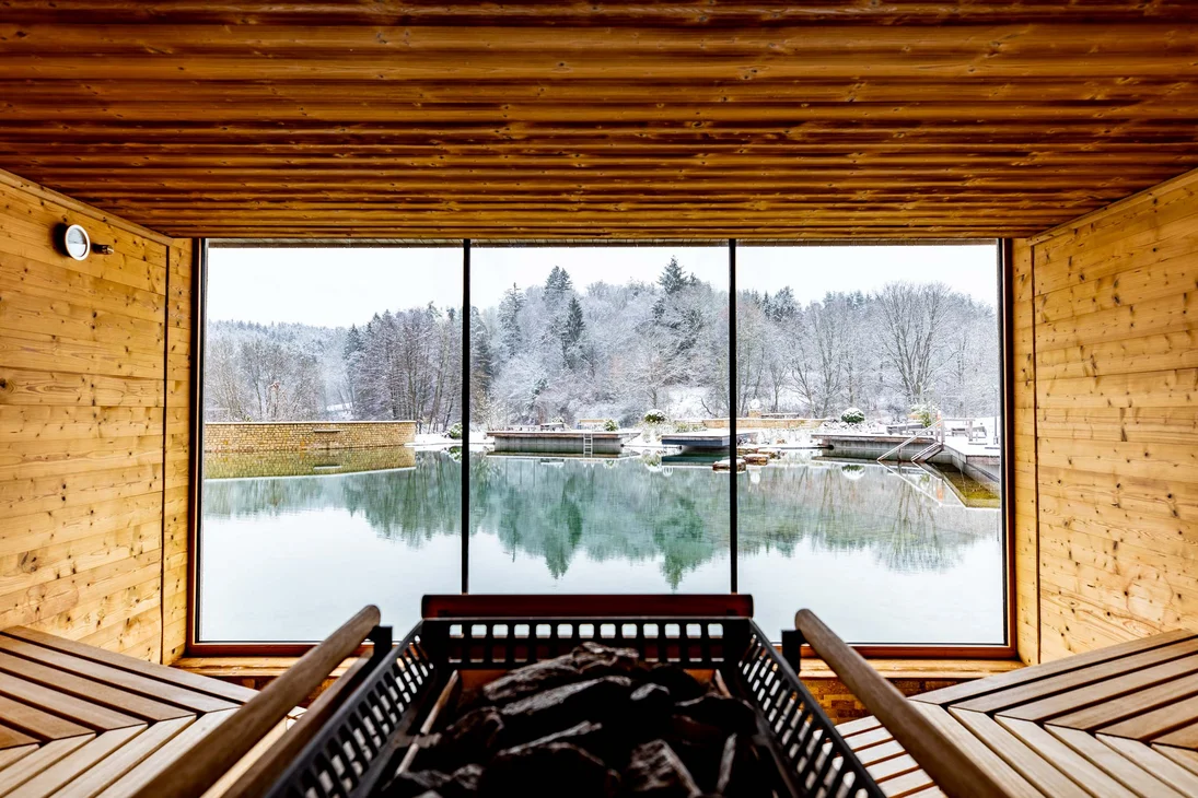 Ihr Hotel im Dahner Felsenland: Pfalzblick Wald Spa Resort Innensauna mit Holzwänden und Blick auf verschneite Landschaft und See
