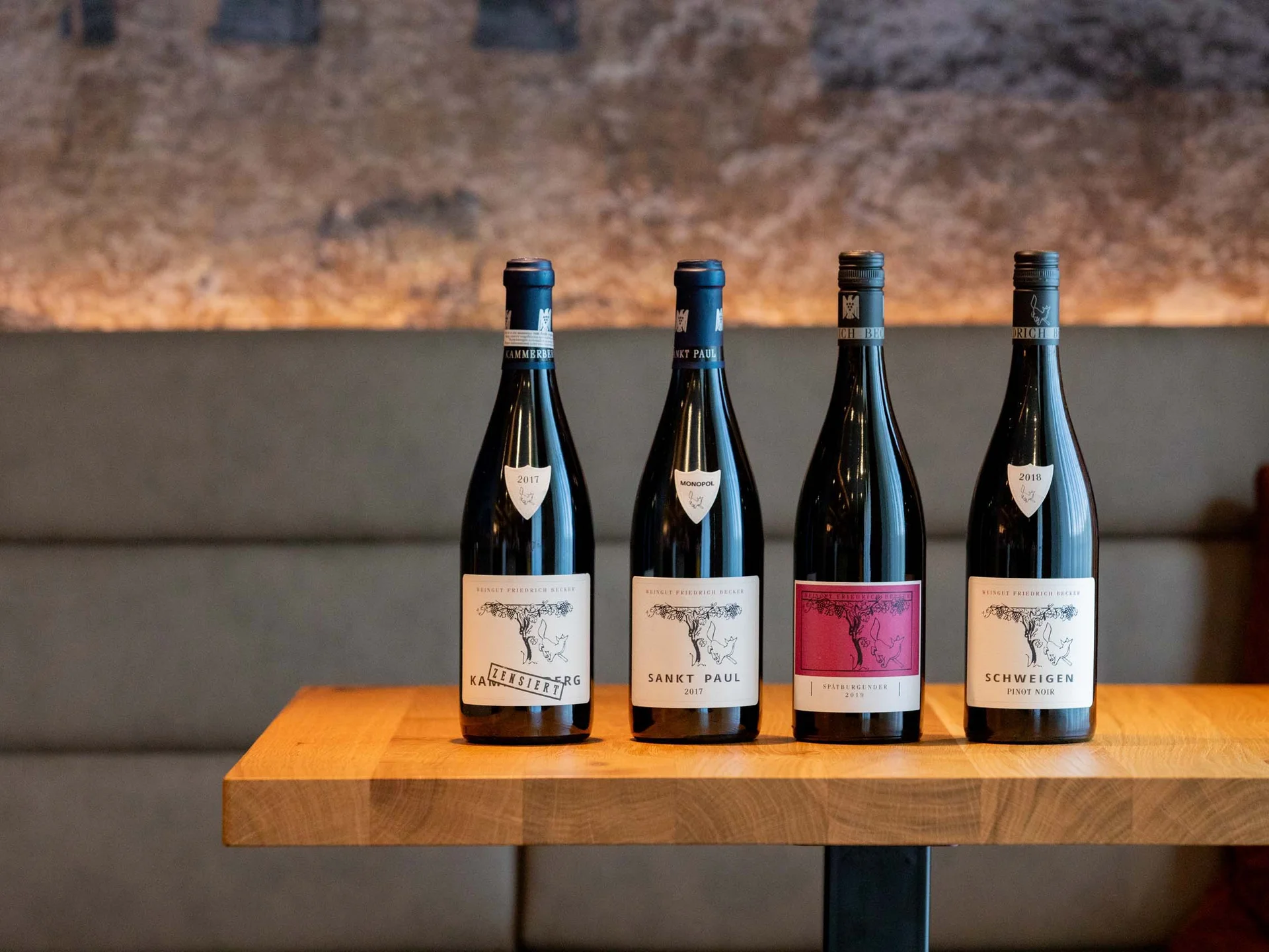 Vacances sur la route des vins dans le Palatinat Four different wine bottles on a wooden table in front of a gray wall