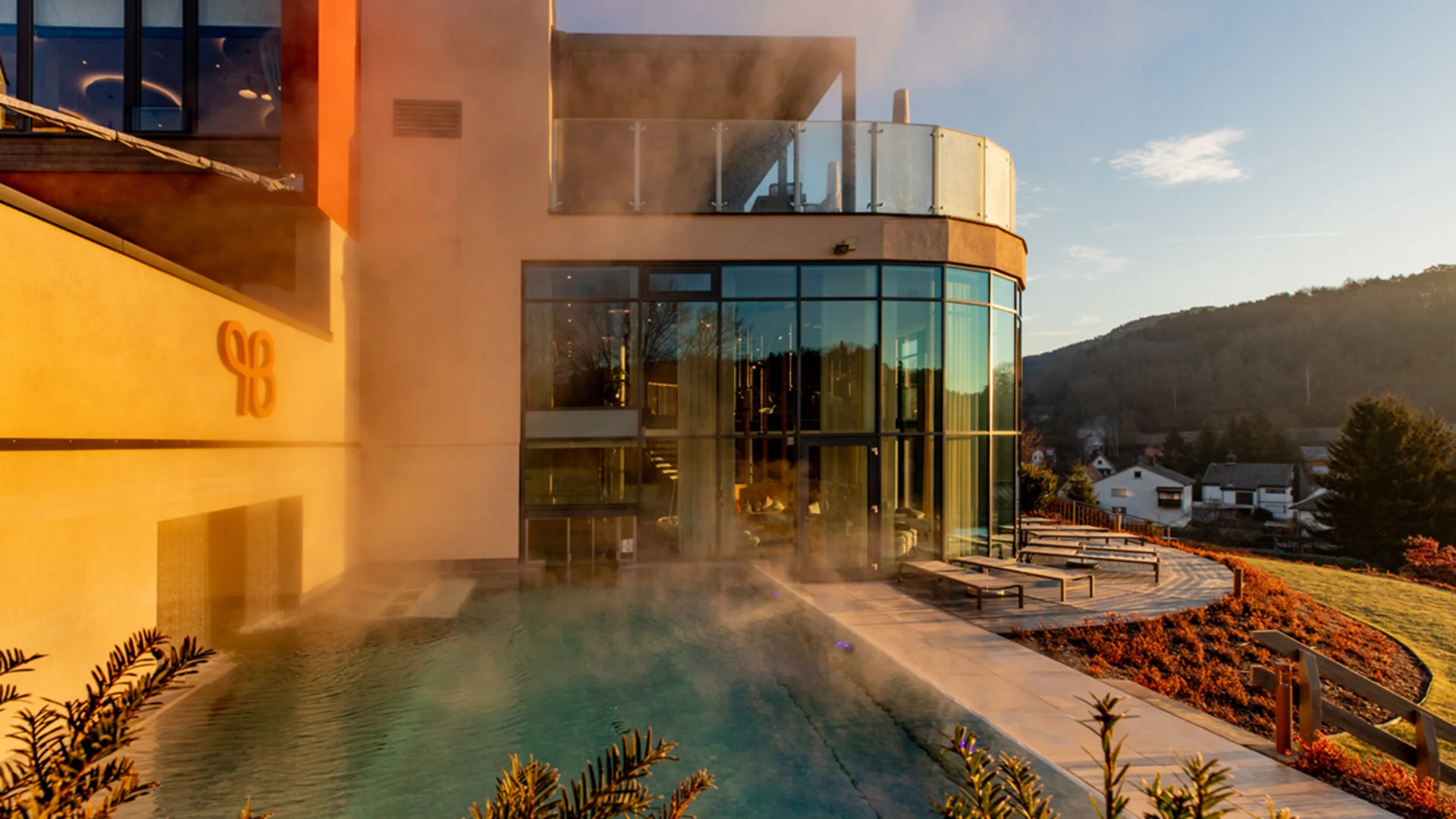 Ihr Hotel im Dahner Felsenland: Pfalzblick Wald Spa Resort Dampfende Poollandschaft neben modernem Gebäude bei Sonnenuntergang